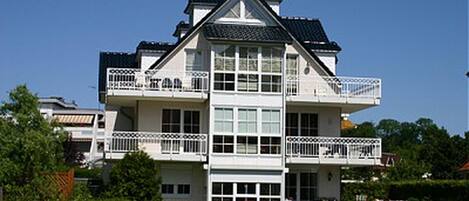 A two-story building with balconies, large windows, and a flat roof.