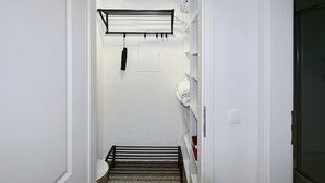 Ein schmaler Flur mit einem Metallhandtuchhalter, einem kleinen Waschbecken und einer Tür zu einem anderen Raum.