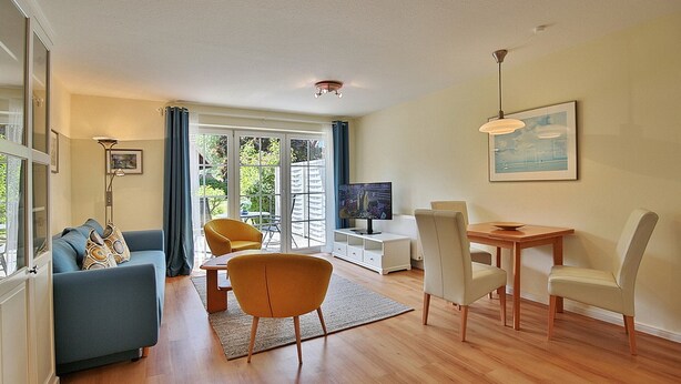 A modern living room with a sofa, chairs, a dining table, and a TV. - Gorch-Fock-Park 57 Apartment 17 Beach pleasure (Timmendorfer Strand)