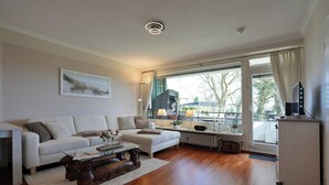 Una sala de estar con un sofá, una mesa de centro y un ventanal con cortinas.