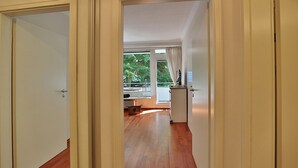 Un pasillo que conduce a una habitación con un ventanal grande, un radiador y un refrigerador pequeño.