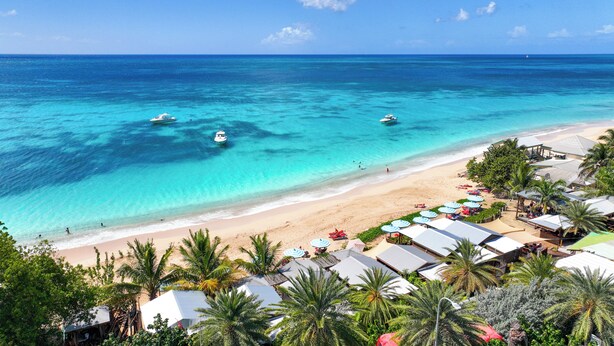 A beach resort with clear turquoise waters, a sandy beach, and several umbrellas and beach chairs. - Conch Beach Cabins - Rumbus Beach (Johnson's Point)