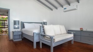 A bedroom with a bed, a nightstand, a chair, a dresser, and a ceiling fan. - Conch Beach Cabins - Rumbus Beach (Johnson's Point)