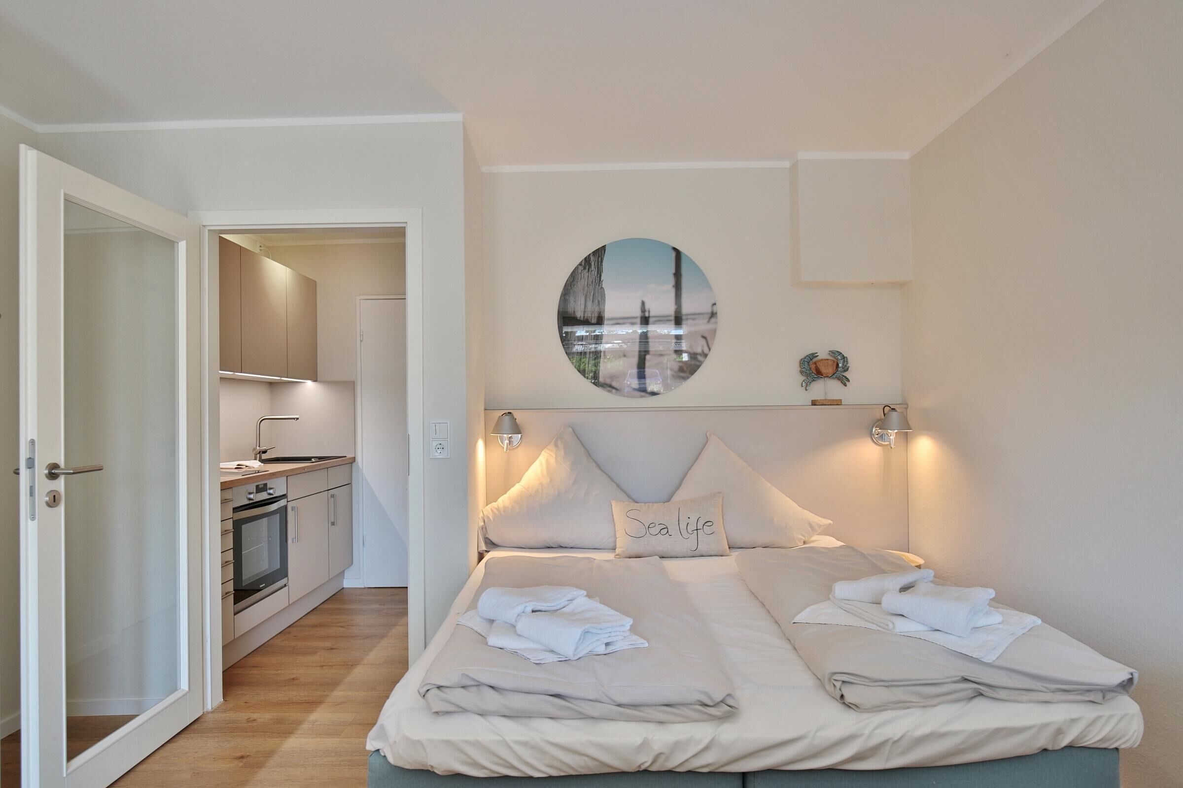 Une chambre à coucher avec un lit, des oreillers, une table de chevet et un tableau accroché au mur.