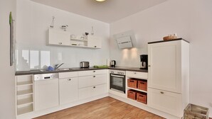 A modern kitchen with white cabinetry, a built-in oven, and a coffee machine. - Die Wolburg Appartement 6 (Timmendorfer Strand)