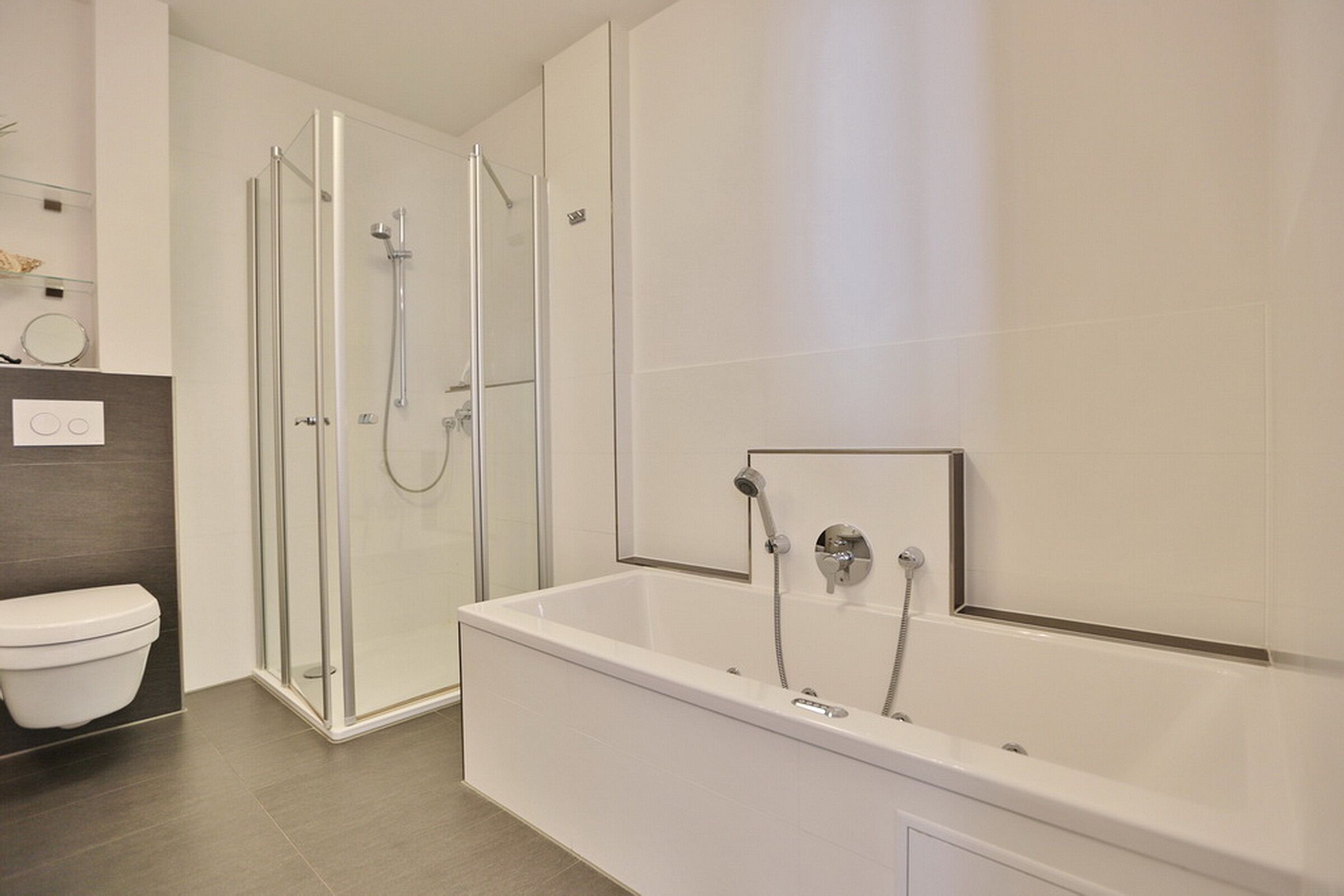 Un baño moderno con ducha envuelta en vidrio, inodoro blanco y bañera independiente.