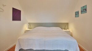 Ein Schlafzimmer mit einem Bett, zwei Nachttischen und Wandbildern.