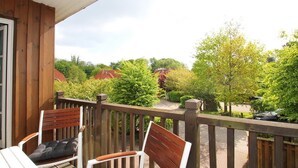 Eine Holzterrasse mit zwei Stühlen und Blick auf eine Wohngegend mit Bäumen und Häusern.