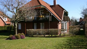 Ein zweistöckiges Haus mit rotem Ziegeldach, einem Balkon und einer Ziegelaußenfassade.