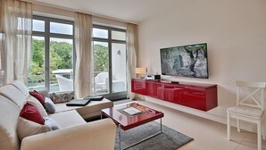 Un salon moderne avec un canapé, une table basse, un meuble de rangement rouge et un téléviseur.