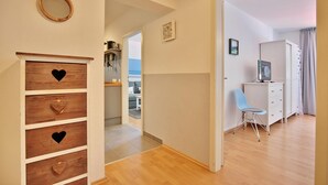 A hallway with wooden cabinets, a mirror, and a blue chair. - Strandkoje Kastanienallee (Timmendorfer Strand)
