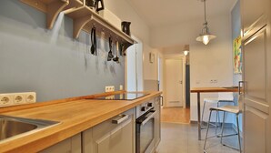 A modern kitchen with a wooden countertop, stainless steel appliances, and a hanging pot rack. - Strandkoje Kastanienallee (Timmendorfer Strand)