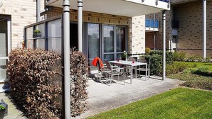 Um edifício moderno com varanda, área de estar ao ar livre e um jardim bem cuidado.
