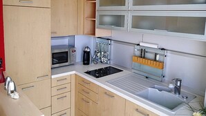 Cozinha compacta com micro-ondas, cafeteira e bloco de facas.