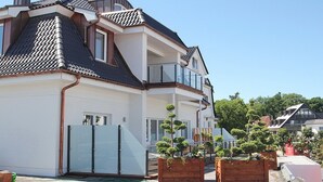 Ein modernes, zweistöckiges Haus mit Balkon, Ziegeldach und Blumentöpfen.