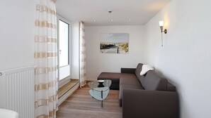 Ein modernes Wohnzimmer mit einer Couch, einem Glastisch und einem Bild an der Wand.