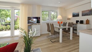 Un salon moderne avec un coin repas, de grandes fenêtres et un téléviseur.