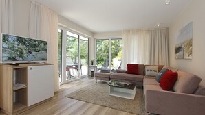 Ein modernes Wohnzimmer mit Flachbildfernseher, einer Couch, einem Couchtisch und einer kleinen Kommode.