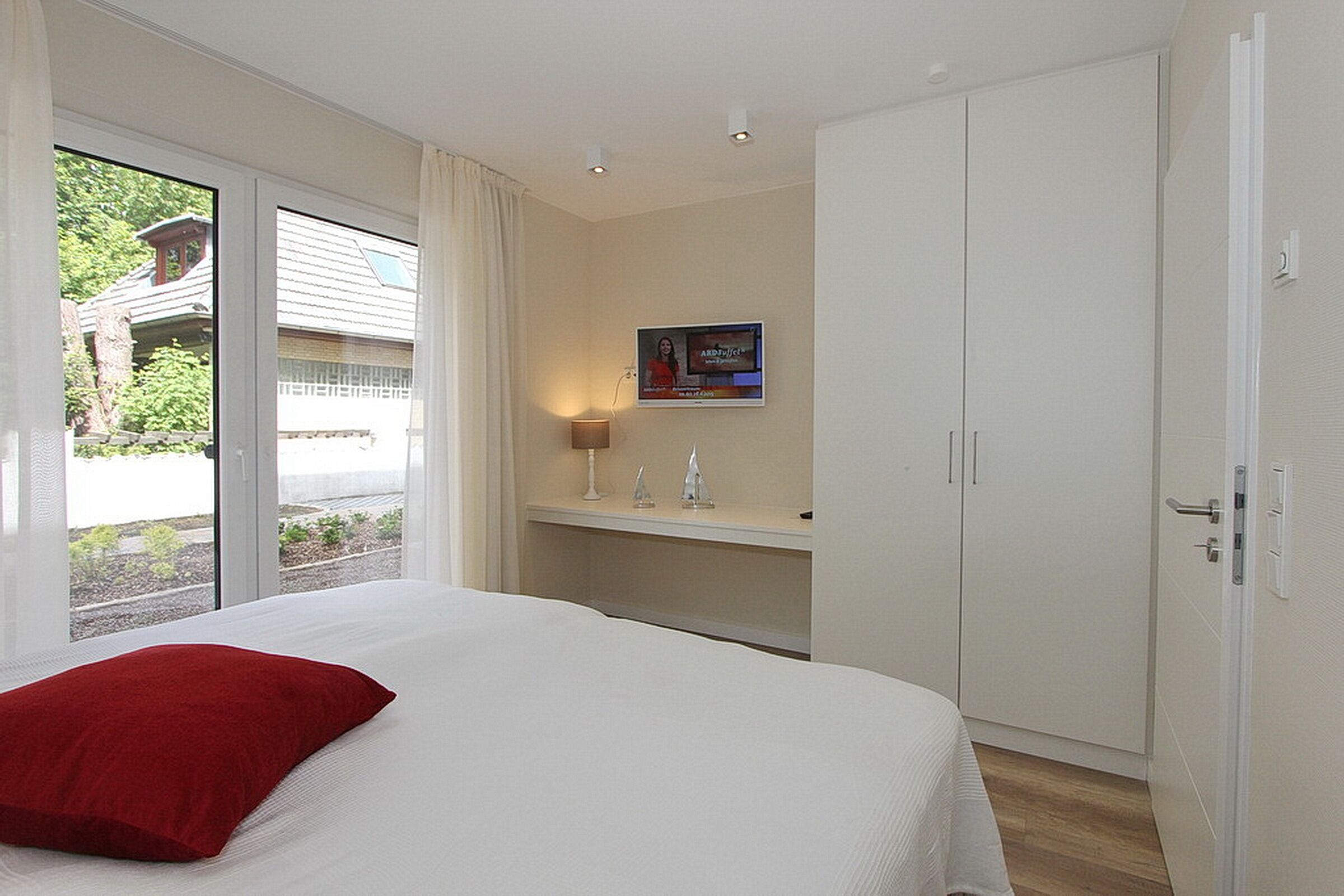Een hotelkamer met een bed, een bureau, een stoel, een lamp en een kledingkast.