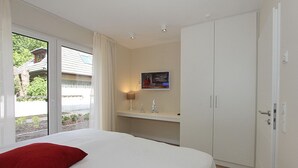 Ein Hotelzimmer mit Bett, Schreibtisch, Stuhl, Lampe und Kleiderschrank.