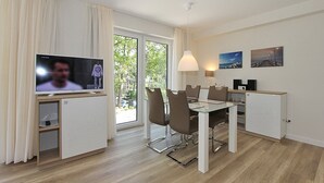 Un espace repas moderne équipé d’un téléviseur, d’une table, de chaises et offrant une vue sur l’extérieur.
