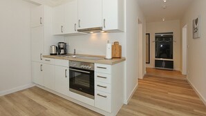 Une cuisine moderne avec des meubles blancs, un four en acier inoxydable et un plan de travail en bois.