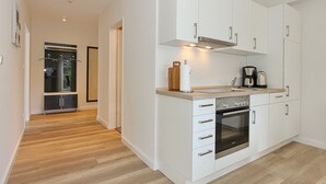 A modern kitchen with white cabinets, a wooden countertop, and stainless steel appliances. - Villa Stern Appartement 12 (Timmendorfer Strand)