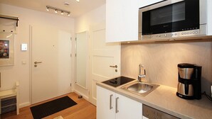 Una cocina compacta con microondas integrado, cafetera y lavabo.