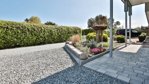 Un jardín bien cuidado con un sendero de grava, setos ordenados y una gran variedad de plantas y flores.