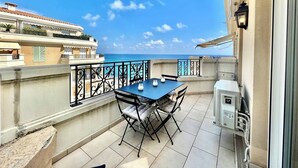 Un balcon avec une table et des chaises, une vue sur la mer et un immeuble doté de balcons.