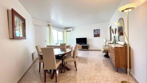 Un coin repas avec une table et des chaises, un téléviseur, un meuble en bois et une lampe sur pied.