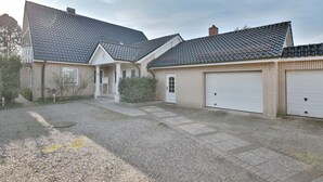Une maison à deux étages, avec un toit en tuiles, un porche à l’avant et un garage.