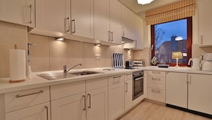 A modern kitchen with white cabinetry, a stainless steel sink, and a built-in oven. - Haus Kastanienallee 3 Appartement 6 (Timmendorfer Strand)