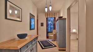 A hallway with a wooden counter, a blue bowl, a framed picture, and a chair. - Haus Kastanienallee 3 Appartement 6 (Timmendorfer Strand)