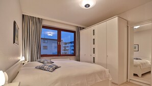 A bedroom with a large bed, a wardrobe, a window with curtains, and a nightlight. - Haus Kastanienallee 3 Appartement 6 (Timmendorfer Strand)