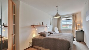 Une chambre à coucher avec un grand lit, une armoire, un bureau et une fenêtre avec des rideaux.