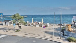 Une promenade en bord de mer avec un passage piéton, des espaces de repos en plein air et une vue sur la mer.
