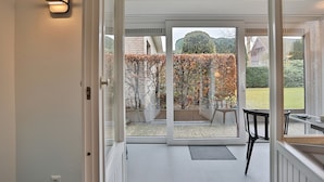 A modern room with a sliding glass door leading to a garden. - Haus Wolburgstrasse Appartement 23 (Timmendorfer Strand)