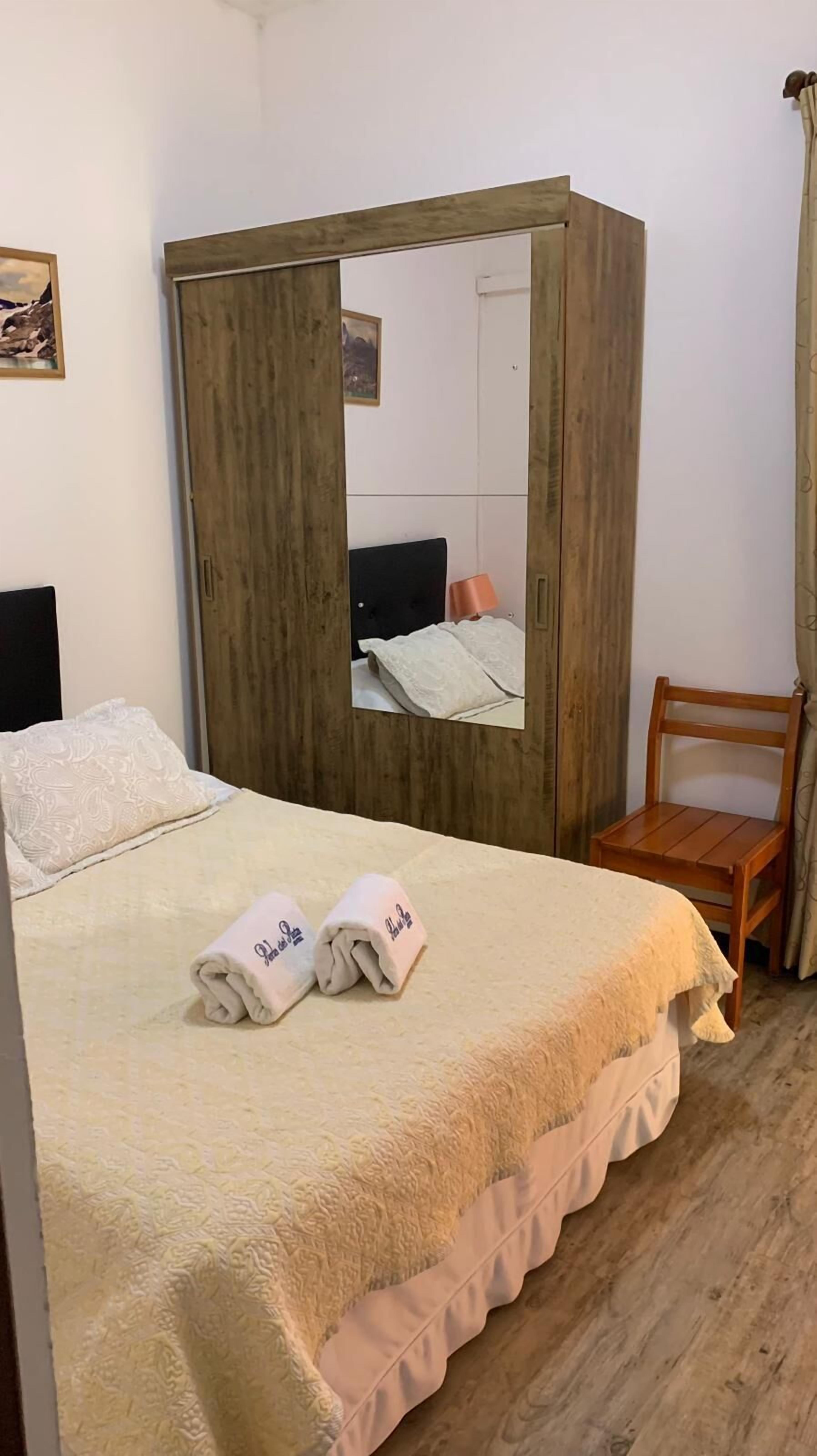 Une chambre à coucher avec un lit, une armoire en bois, une chaise et un miroir.