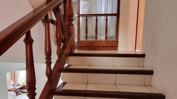 Una escalera de madera con barandilla y una puerta de cristal con el cartel de un hotel.