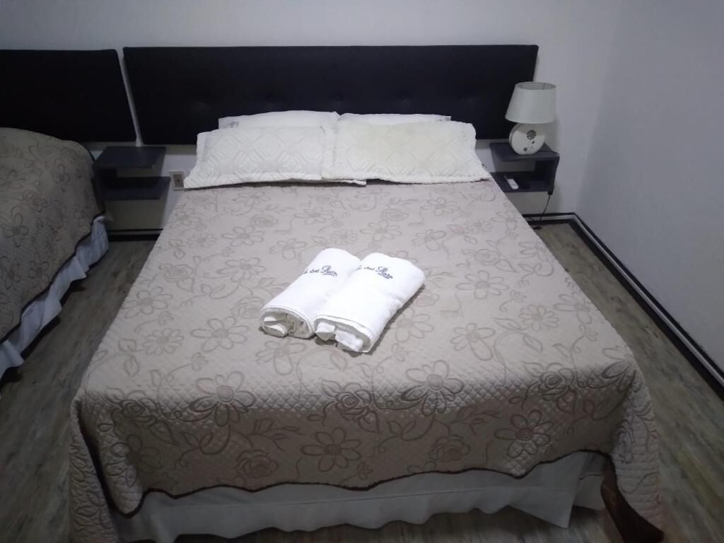 A neatly made bed with a floral-patterned bedspread and two folded towels on it.