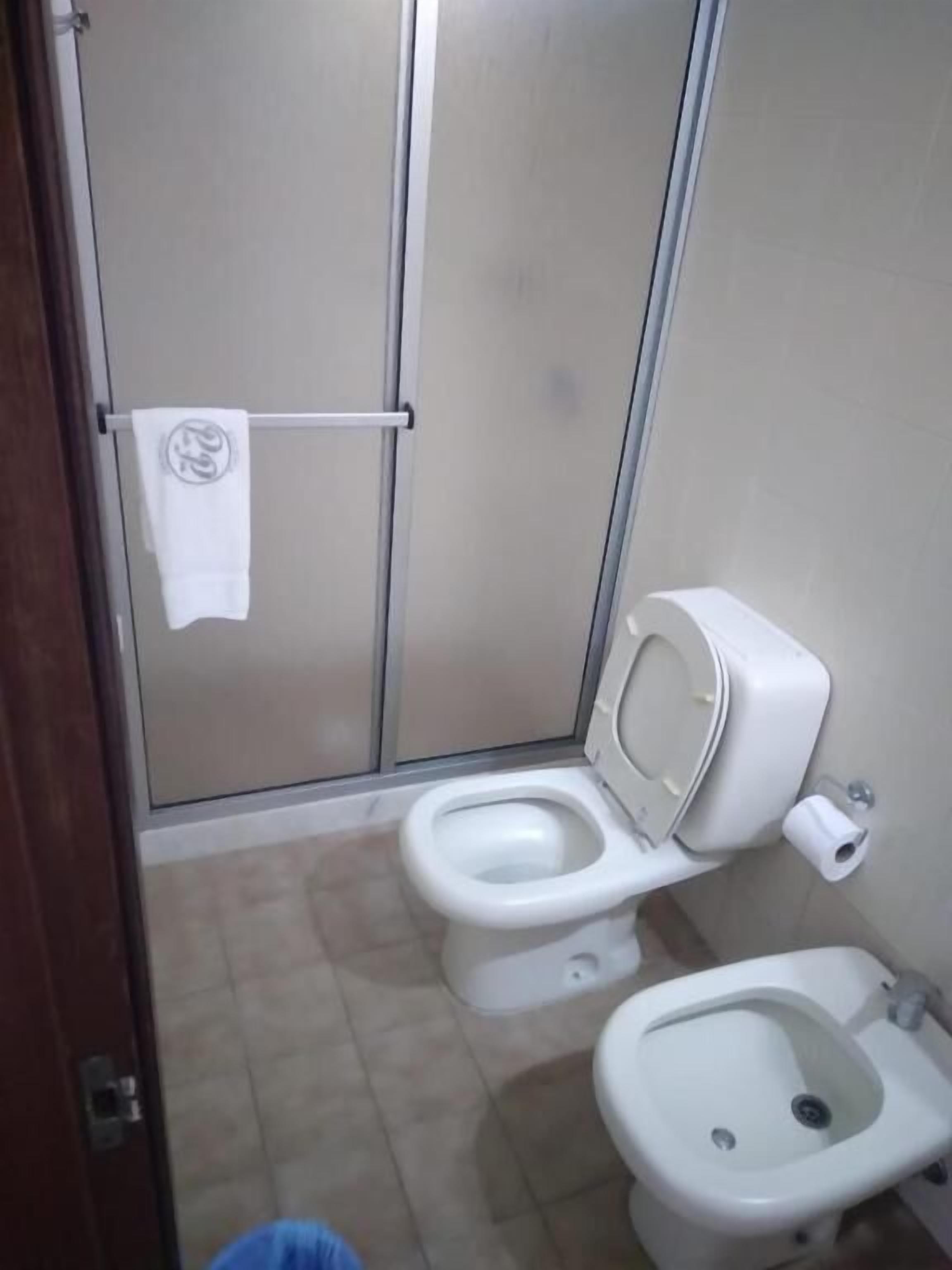 A bathroom with a toilet, bidet, and a towel hanging on a rack.