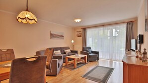 En moderne stue med sofa, lænestole, sofabord og spiseplads.