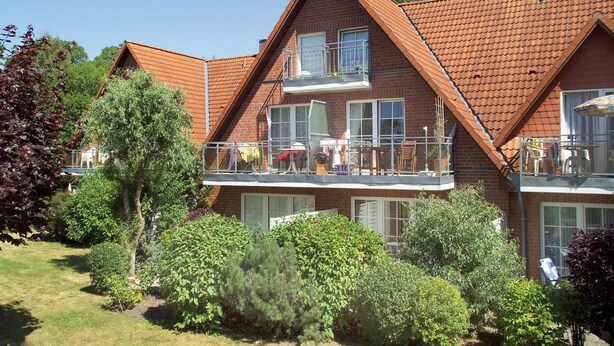 Et toetagers hus med balkon, omgivet af grønt.