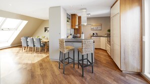 A modern kitchen with a dining area, wooden flooring, and a skylight. - Your rooftop penthouse in Vienna 2 (Wien)