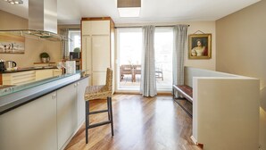 A modern kitchen with a glass-top island, wooden flooring, and a dining area with a bench and curtains. - Your rooftop penthouse in Vienna 2 (Wien)