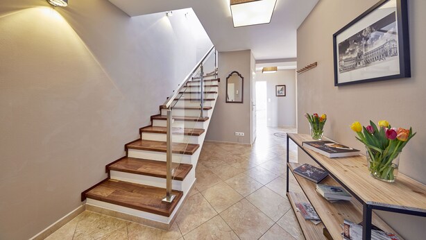 A staircase with wooden steps and metal railings, leading to a landing with a framed picture and a vase of tulips. - Your rooftop penthouse in Vienna 2 (Wien)