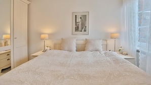 Une chambre à coucher avec un grand lit, deux tables de chevet avec des lampes, une armoire et un tableau encadré au mur.