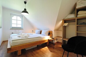 A bedroom with a wooden bed, a small desk, a chair, a radiator, a window, and a built-in wardrobe. - Am Rosenhain 23 Appartement 5 (Timmendorfer Strand)