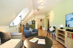 A modern living room with a sofa, armchair, coffee table, and a television. - Am Rosenhain 23 Appartement 5 (Timmendorfer Strand)